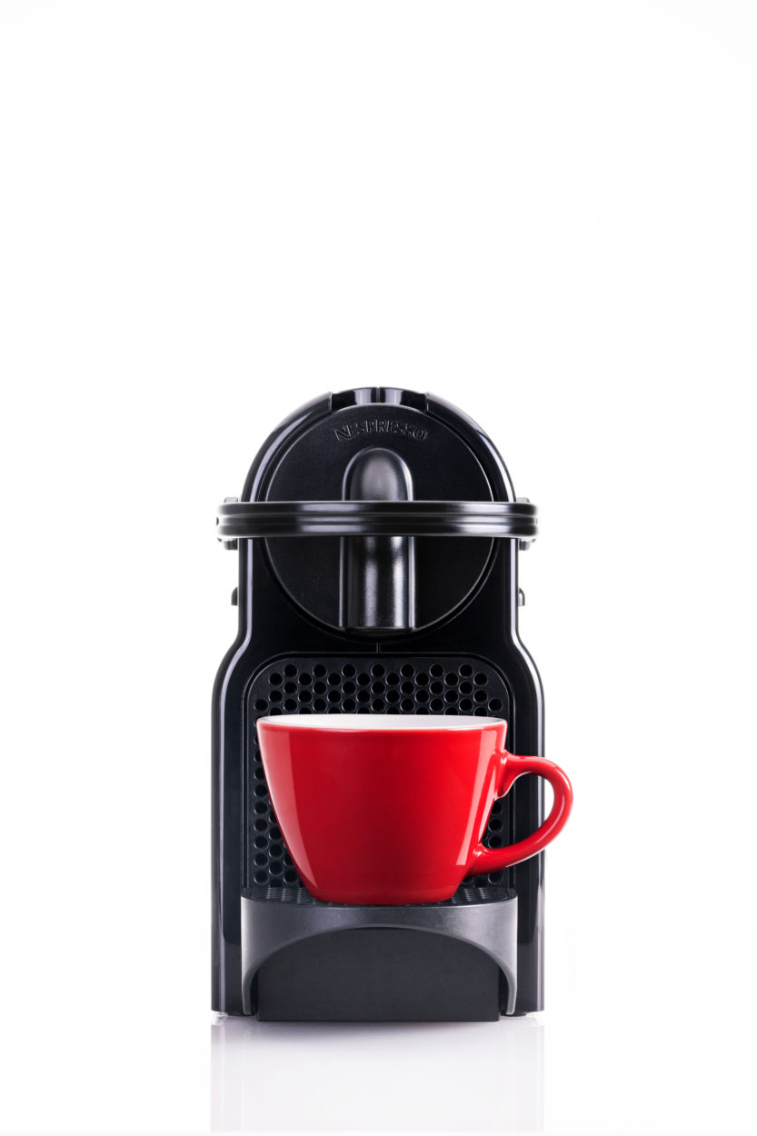 a clean product photo of a nespresso machine with a red cup