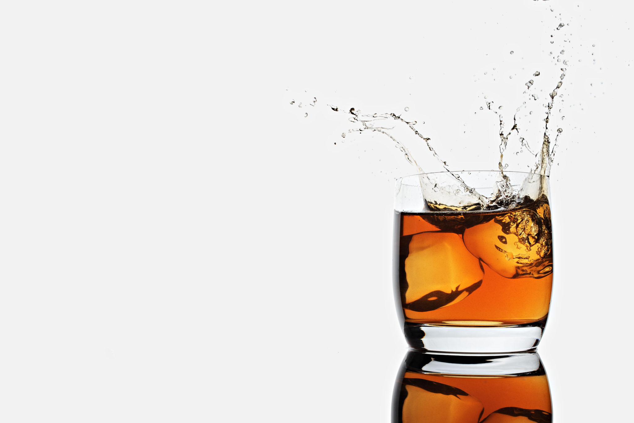 ice cubes splash in a glass cup of whisky