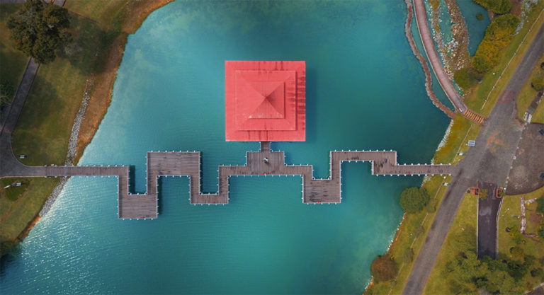Top down aerial shot of a bridge and shelter across a small lake