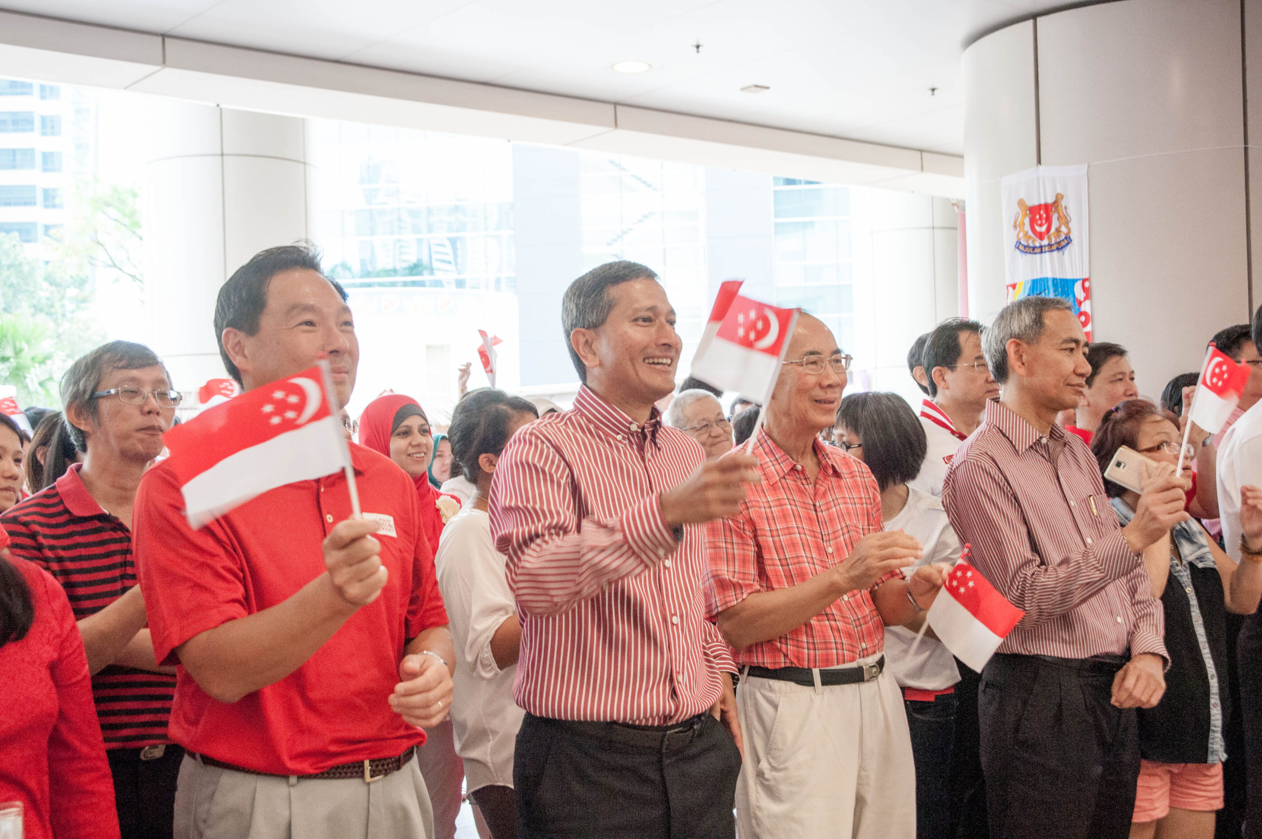 Dr Vivian Balakrishnan and the crowd waving the Singapore flag in a national day event