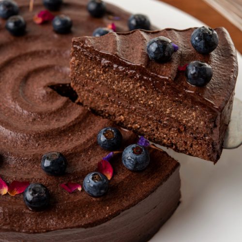 Professional food photography lifting a slice of chocolate and blueberry cake